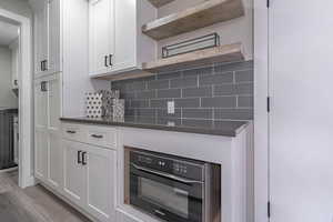 Kitchen featuring tasteful backsplash, beverage cooler, light hardwood / wood-style flooring, and white cabinets