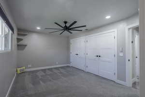 Interior space with ceiling fan, dark carpet, and multiple closets