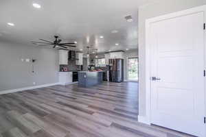 Unfurnished living room featuring light hardwood / wood-style floors, sink, and ceiling fan