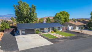 Single story home with a front yard, a mountain view, and a garage