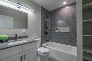 Full bathroom featuring vanity, tiled shower / bath combo, and toilet