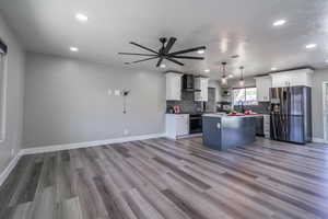 Kitchen with pendant lighting, stainless steel appliances, white cabinetry, and a kitchen island