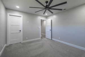 Carpeted spare room featuring ceiling fan