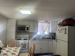 Kitchen featuring backsplash, white appliances, white cabinetry, and sink