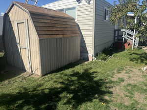 View of property exterior with a storage unit and a yard