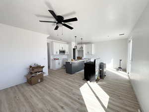 Kitchen with a kitchen island, pendant lighting, white cabinets, ceiling fan, and light wood-type flooring