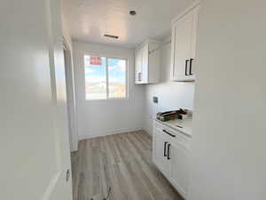 Laundry area featuring hookup for a washing machine, cabinets, and light hardwood / wood-style flooring