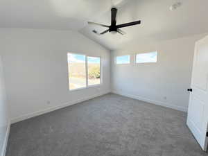 Carpeted empty room with lofted ceiling and ceiling fan