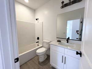 Full bathroom with hardwood / wood-style flooring, vanity, toilet, and shower / washtub combination