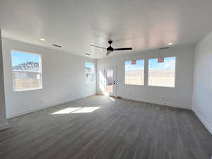 Unfurnished living room with dark wood-type flooring, a wealth of natural light, a textured ceiling, and ceiling fan