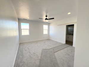 Spare room featuring light carpet, a textured ceiling, and ceiling fan