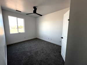 Carpeted spare room with a textured ceiling and ceiling fan