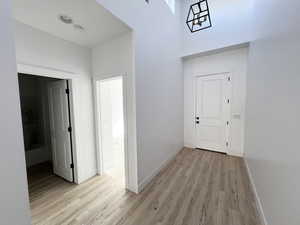 Hall featuring light hardwood / wood-style flooring and a high ceiling