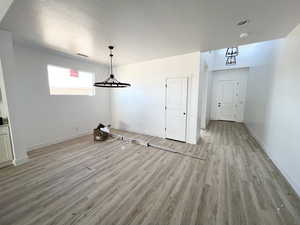 Unfurnished dining area with light hardwood / wood-style floors and a textured ceiling