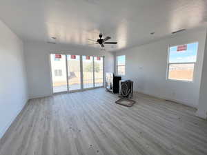 Unfurnished living room featuring ceiling fan, a textured ceiling, and light wood-type flooring