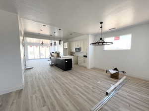 Kitchen with white cabinetry, a kitchen island, a wealth of natural light, and pendant lighting