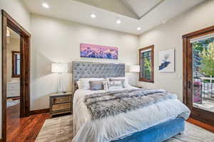 Bedroom with access to outside, vaulted ceiling, and dark hardwood / wood-style flooring