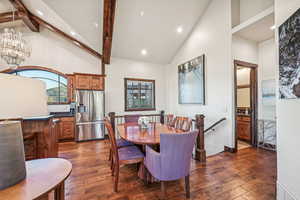 Dining space with beamed ceiling, a chandelier, dark hardwood / wood-style flooring, and high vaulted ceiling