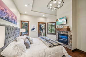 Bedroom featuring a fireplace, an inviting chandelier, and dark wood-type flooring