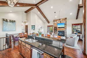 Kitchen with an island with sink, a fireplace, sink, and dark hardwood / wood-style flooring