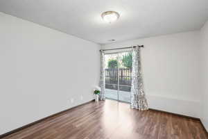 Unfurnished room featuring wood-type flooring and a textured ceiling