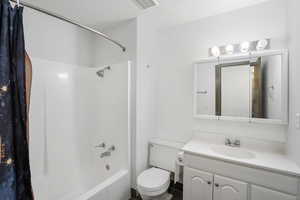 Full bathroom with vanity, shower / bath combo with shower curtain, toilet, and a textured ceiling