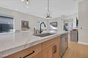 Kitchen with ceiling fan, light stone counters, sink, dishwasher, and light wood-type flooring