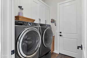 Laundry area featuring dark hardwood / wood-style floors, independent washer and dryer, and cabinets