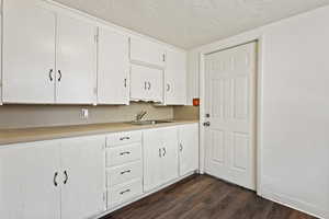 Kitchen with sink, dark hardwood / wood-style flooring, a textured ceiling, and white cabinetry