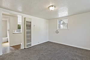 Unfurnished room with dark carpet and a textured ceiling