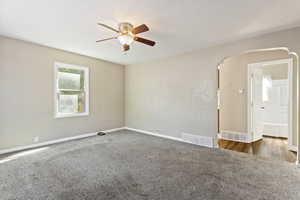 Empty room with a textured ceiling, ceiling fan, and dark hardwood / wood-style flooring