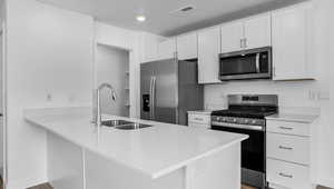 Kitchen with stainless steel appliances, white cabinetry, kitchen peninsula, and sink