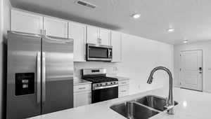 Kitchen featuring appliances with stainless steel finishes, a textured ceiling, sink, and white cabinets