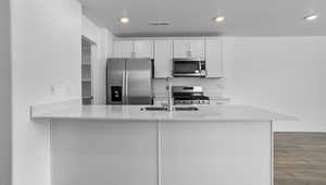 Kitchen with white cabinets, stainless steel appliances, a textured ceiling, hardwood / wood-style flooring, and sink