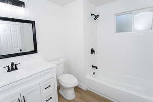 Full bathroom with wood-type flooring, tiled shower / bath, vanity, and toilet