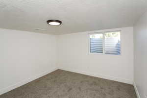 Carpeted spare room featuring a textured ceiling