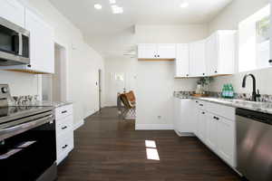 Kitchen with light stone countertops, white cabinets, and appliances with stainless steel finishes