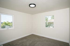 Carpeted empty room featuring a textured ceiling and plenty of natural light