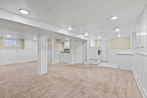 Basement with light colored carpet and washing machine and dryer