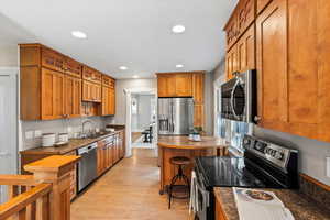 Kitchen featuring l, sink, stainless steel appliances, and a kitchen bar