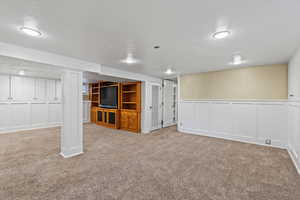 Basement with light colored carpet and a textured ceiling