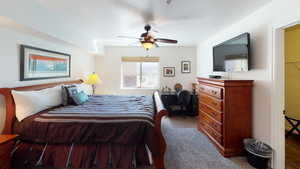 Carpeted bedroom with ceiling fan and a textured ceiling