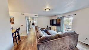 Living room with a textured ceiling and hardwood / wood-style flooring