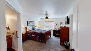 Bedroom with a textured ceiling, carpet, and ceiling fan