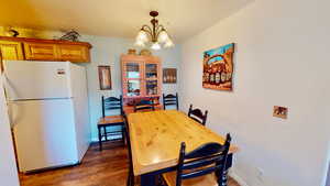 Dining area with dark wood-type flooring and a chandelier