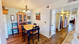 Dining area with dark wood-type flooring and a notable chandelier