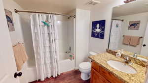 Full bathroom with shower / bath combination with curtain, vanity, toilet, a textured ceiling, and hardwood / wood-style floors