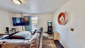 Living room with a textured ceiling and dark wood-type flooring