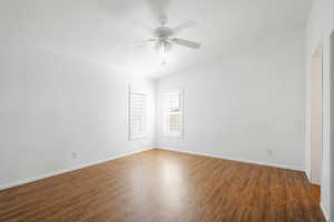 Empty room with vaulted ceiling, ceiling fan, and dark hardwood / wood-style flooring