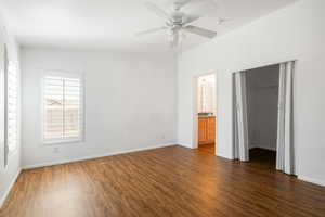 Unfurnished bedroom featuring ceiling fan, lofted ceiling, dark wood-type flooring, a closet, and ensuite bathroom